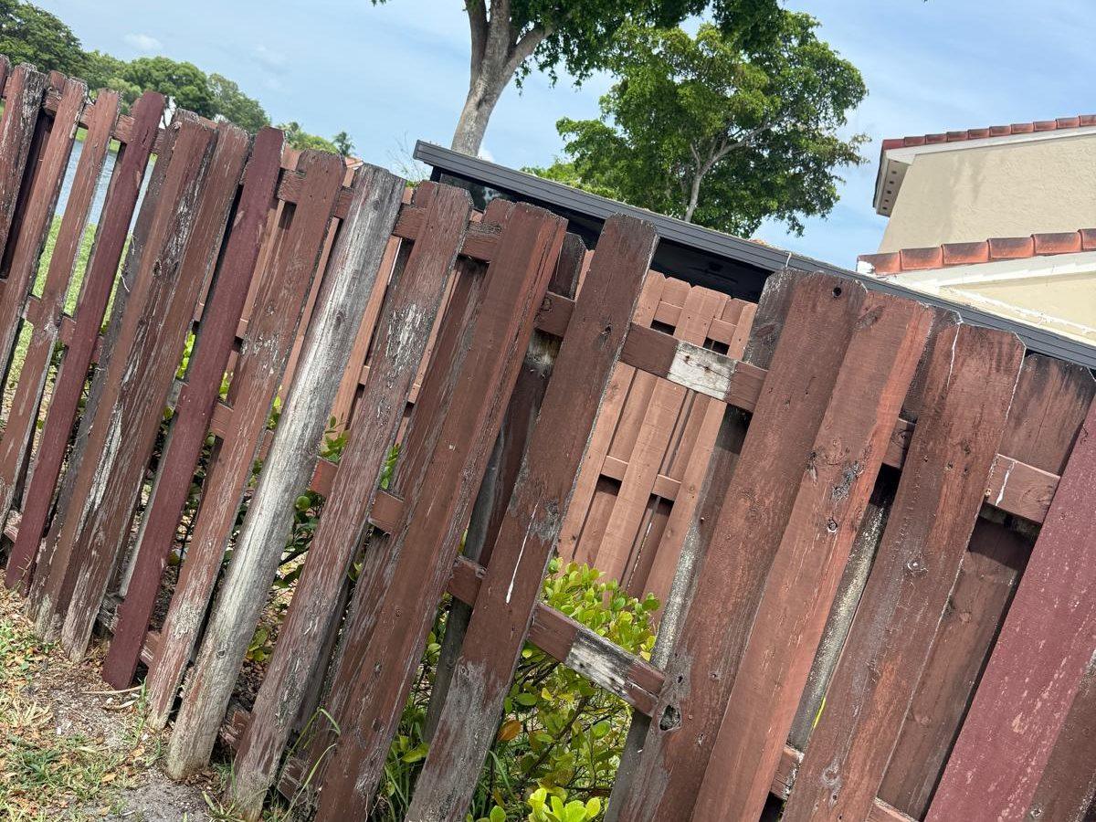 Broken and leaning fence boards before repair